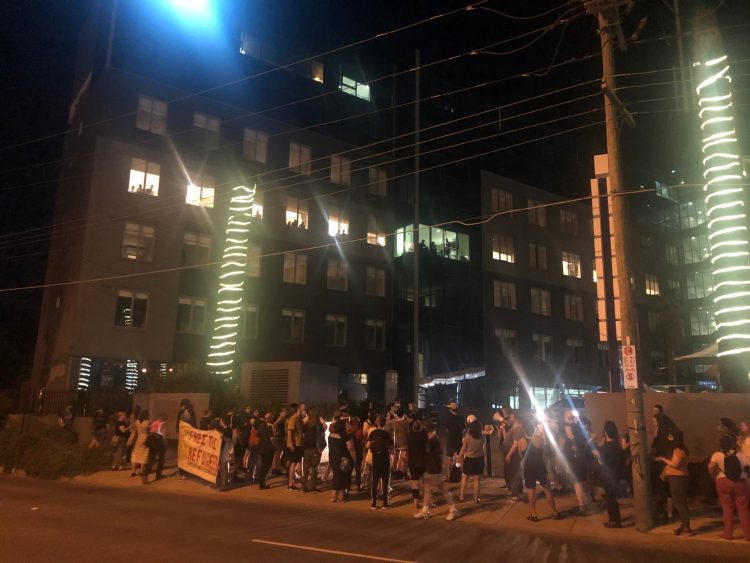 Refugee advocates  hold a vigil outside the Mantra hotel in Melbourne this week, amid concern that “Medevac” refugees – watching from the windows above – were going to be suddenly moved to a new facility. Photo: Marie McInerney