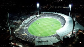 A green sports oval is lit up with bright lights against a black sky